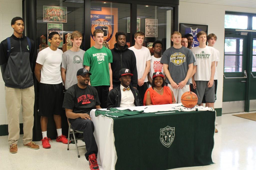 Senior Tre Ivory, seated at the table, is surrounded by relatives and teammates as he commits to play basketball at Austin Peay.